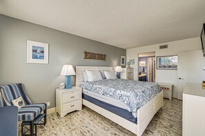 A bedroom with a bed, bedside tables, a chair, a dresser, and a wall-mounted sign.