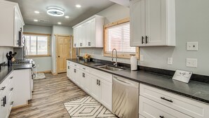 Een moderne keuken met witte kasten, een zwart aanrecht en een houten vloer.