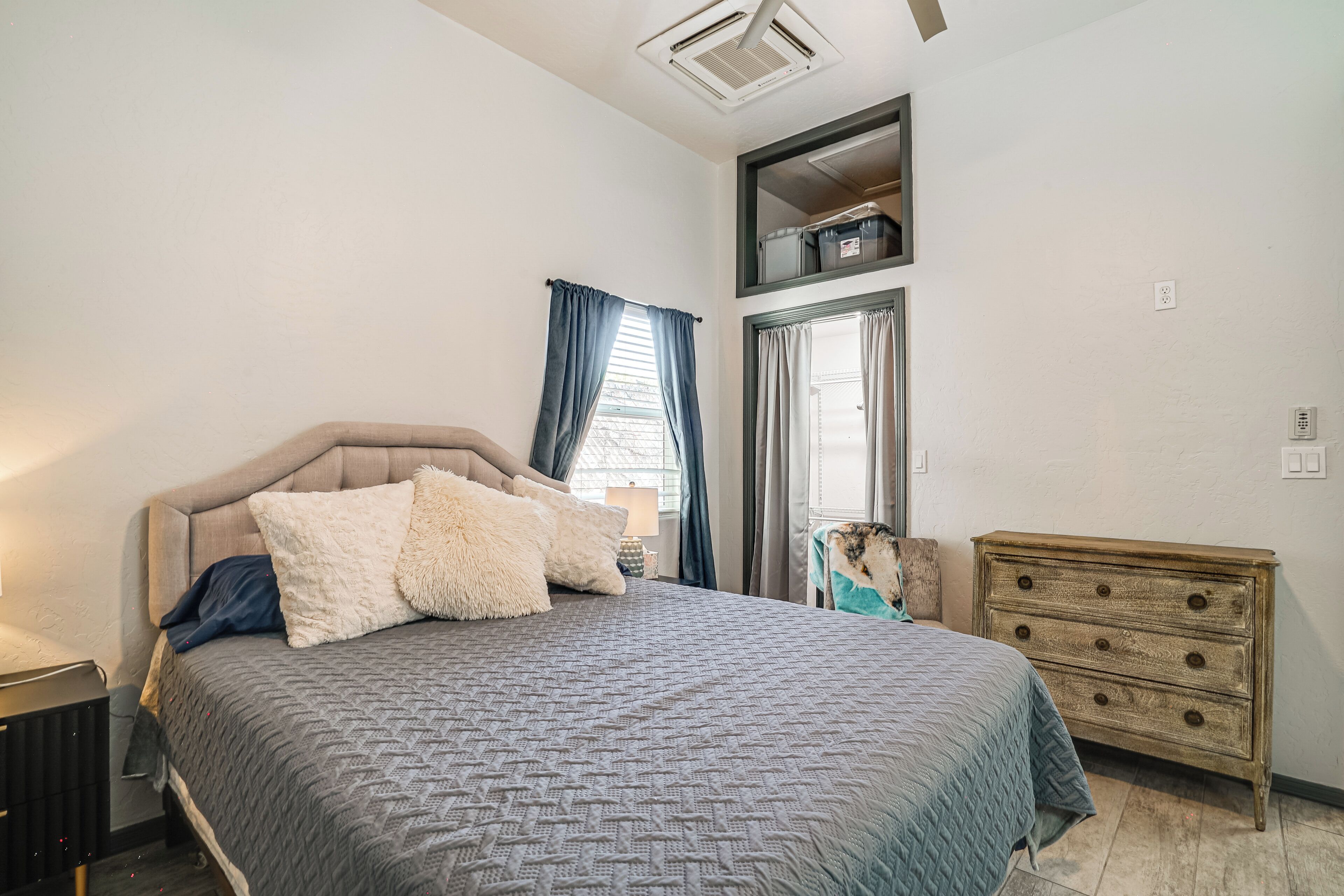 Un dormitorio con cama, cómoda y ventana con cortinas.