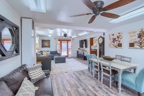 A spacious living area with a ceiling fan, a dining table with chairs, a sofa, and a large window with curtains. - Group Getaway w/ Mtn Views: Home in Circleville! (Circleville)