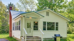 Ein kleines, eingeschossiges Haus mit Veranda, Schornstein und Grill.