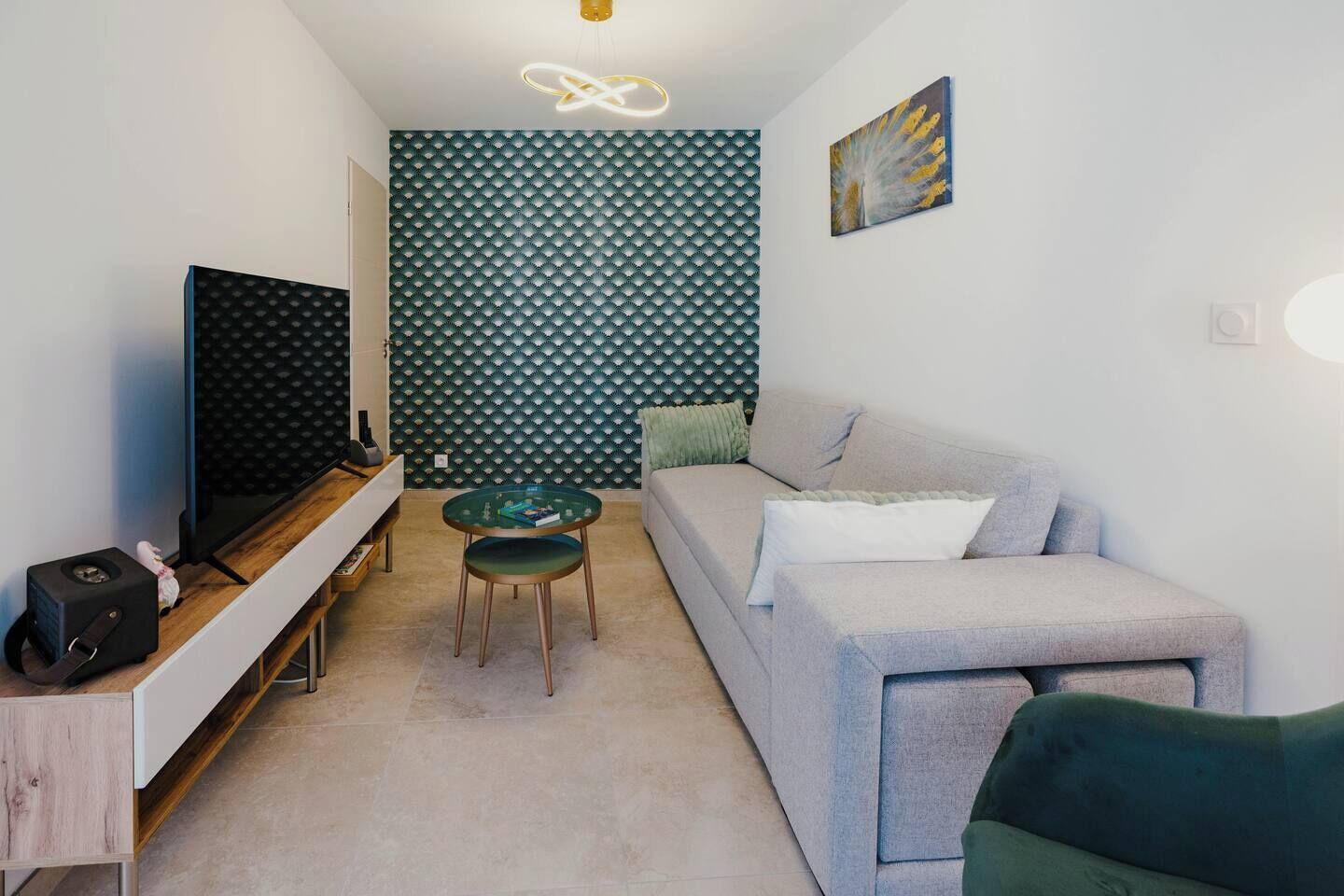 A compact living space with a sofa, a glass coffee table, a TV, and a patterned wall.