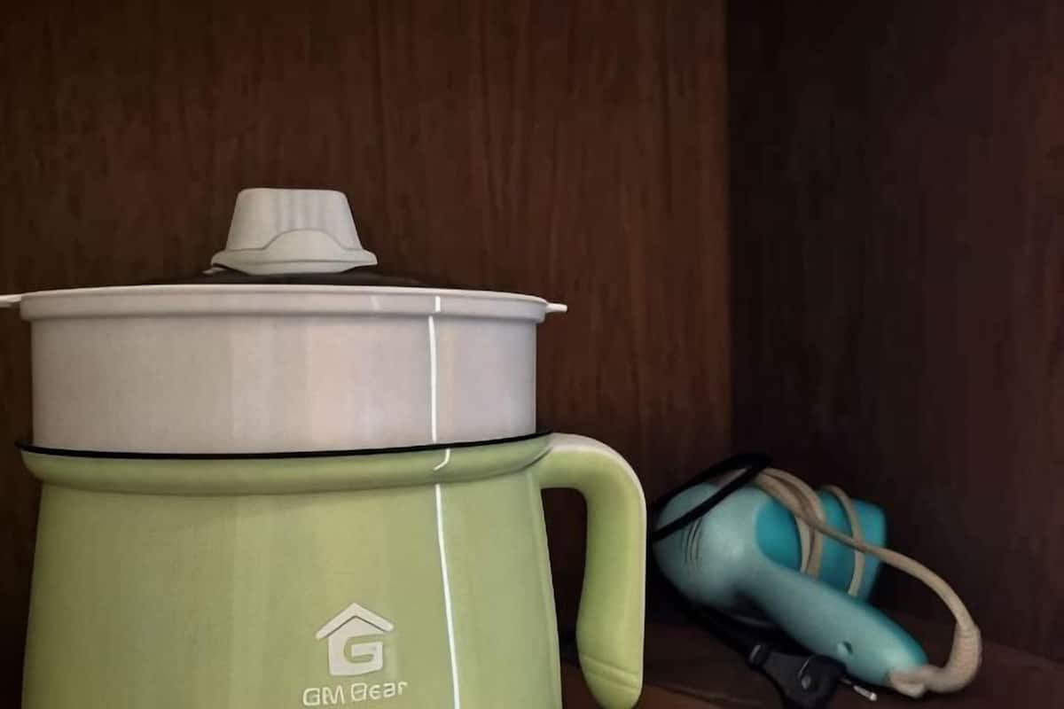 Una olla de cocción lenta GABA Bear verde con tapa y asa, sobre una superficie de madera junto a una bolsa color turquesa.