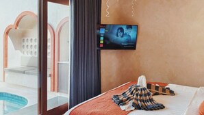 Ein modernes Hotelzimmer mit einem großen Bett, einem an der Wand befestigten Fernseher und einem Balkon mit Pool.