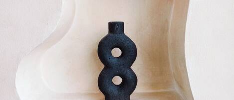 A unique, abstract wall sculpture with a light-colored base and a black, circular object on top.