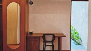 Ein kleiner Raum mit Schreibtisch, Stuhl und einem kleinen Schrank. Eine Klimaanlage ist an der Wand über dem Schreibtisch angebracht.