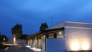 A modern building with a covered outdoor seating area and a well-lit entrance. - Tenuta Petra Chiara -Apulian Country B&B (Nardo)