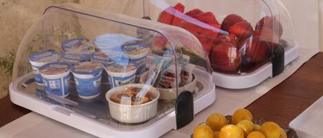 A buffet with covered food items including yogurt, Nutella, and fruits.