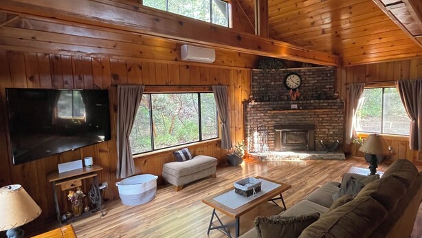 A wooden cabin interior with a large TV, a fireplace, and a sofa.