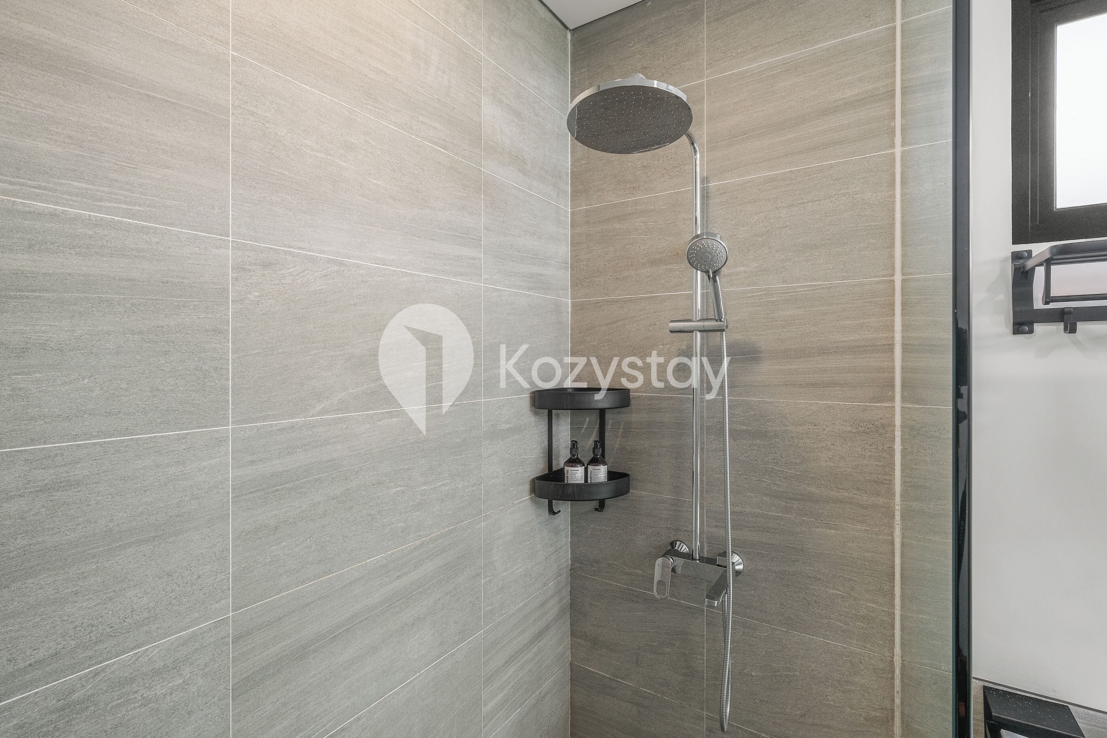Un bagno moderno con doccia, rivestito di piastrelle e dotato di un piccolo ripiano con flaconi.