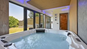 Moderni spa-huone, jossa on poreallas, suuret ikkunat ja näkymä ulos.