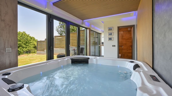 A modern spa room with a hot tub, large windows, and a view of the outdoors.