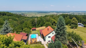 A residential property with a swimming pool, multiple buildings, and a surrounding landscape.