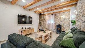 A living room with a stone wall, a fireplace, a television, and a sofa. - Villa Elefant by Villas Guide (Tribalj)