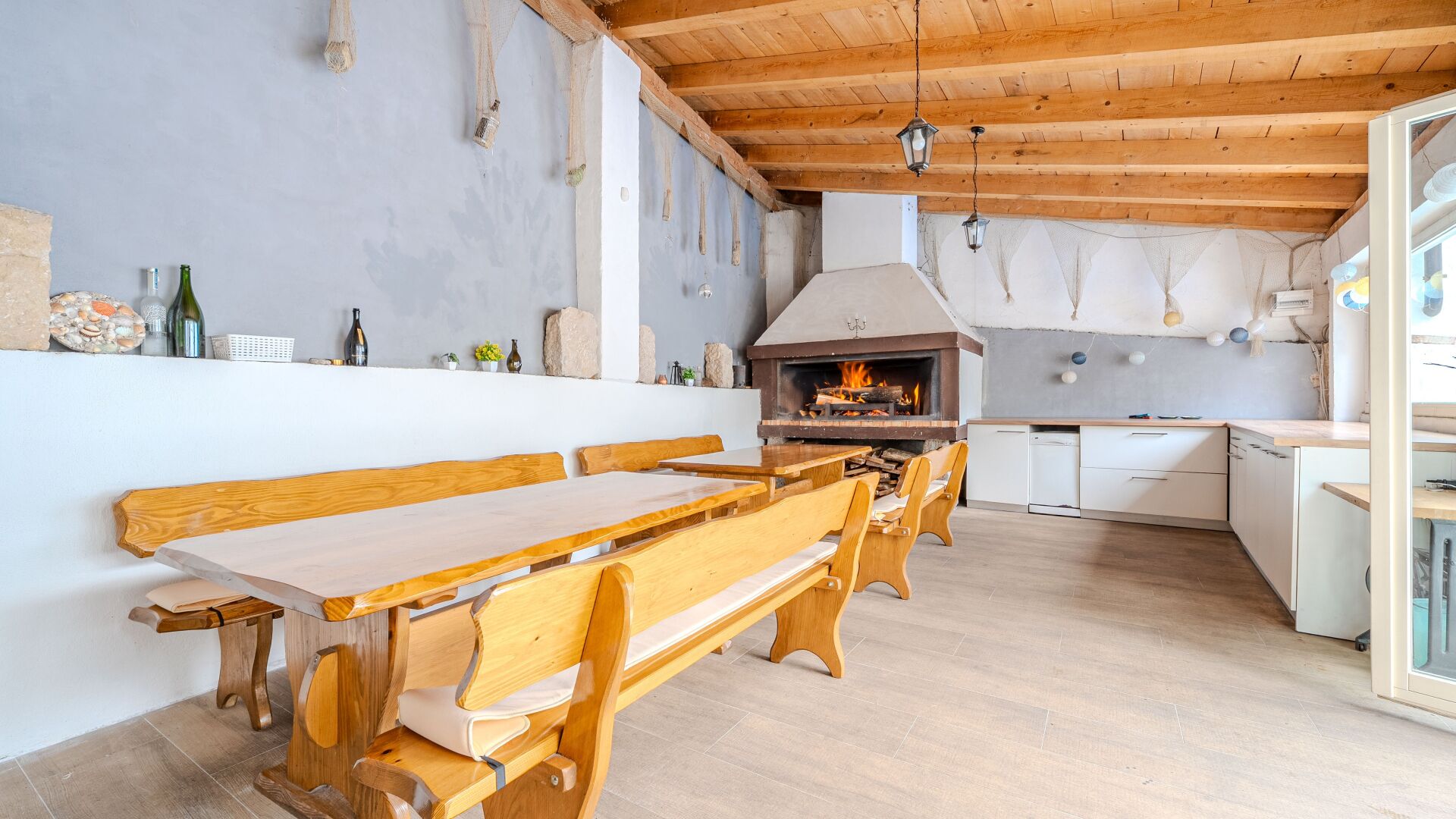Una cocina rústica con estufa de leña, bancos de madera y una encimera blanca.