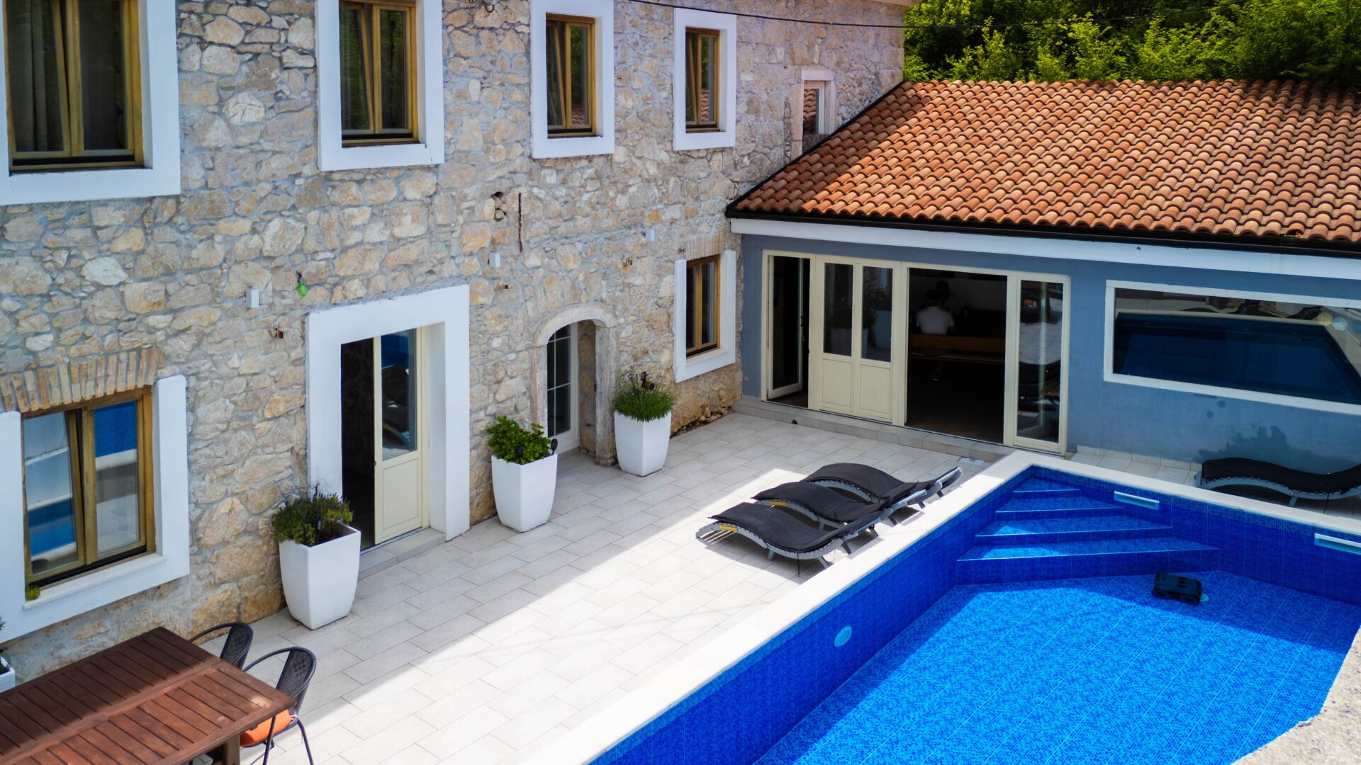 Un edificio de piedra con piscina, terraza techada y zona de comedor.