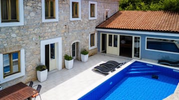 Un edificio de piedra con piscina, terraza techada y zona de comedor.