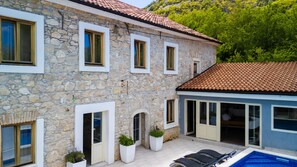 A stone building with a pool, large windows, and a tiled roof. - Villa Elefant by Villas Guide (Tribalj)