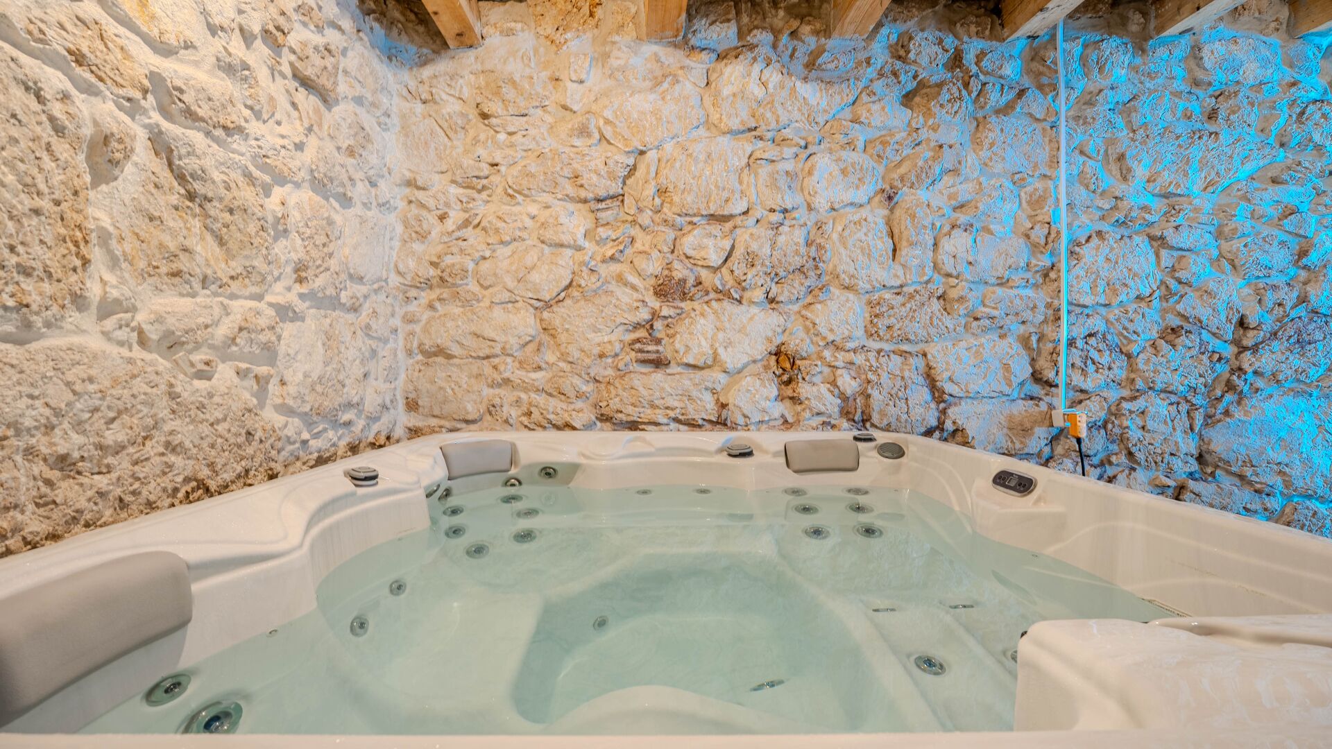 Una habitación de paredes de piedra con una bañera de hidromasaje.