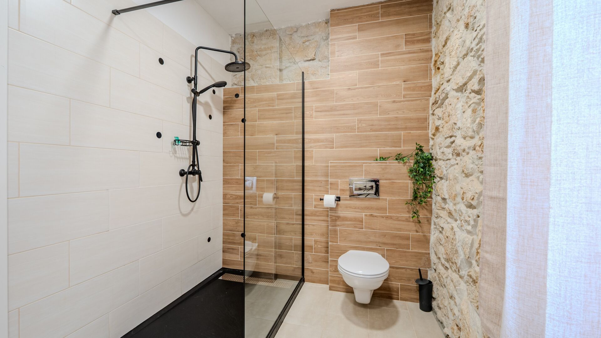 A modern bathroom with a shower, toilet, and a stone accent wall.