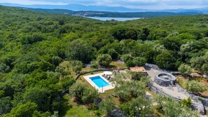 A pool surrounded by stone walls, with a view of a lake and mountains in the distance. - Villa Verde Oliva Residence by Villas Guide (Dobrinj)