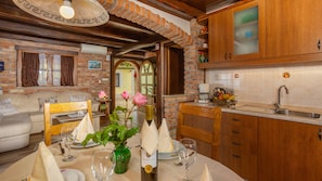 A cozy dining area with a brick wall, wooden furniture, and a table set for two with a vase of flowers. - Casa Milena 1 Lovran Opatija by Villas Guide (Liganj)