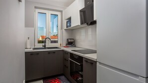 Una cocina compacta con lavamanos, estufa, microondas y horno.