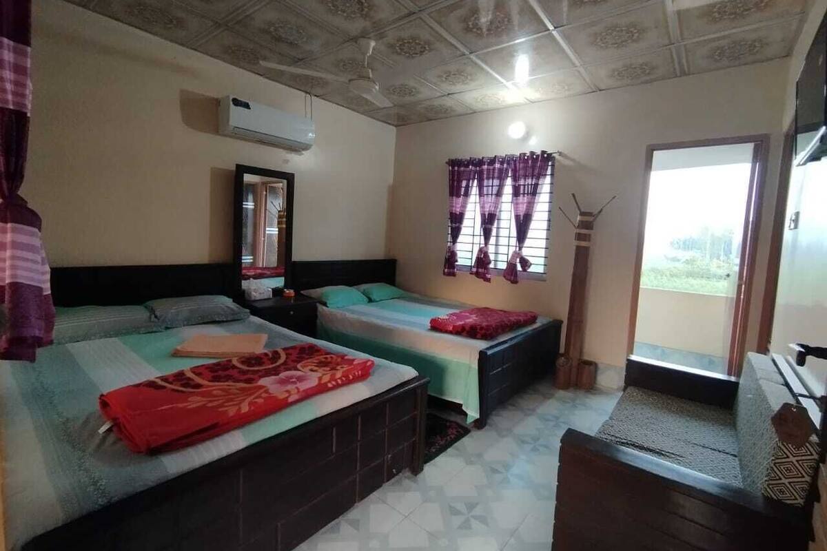 A room with two beds, a ceiling fan, an air conditioning unit, and a window with purple curtains.