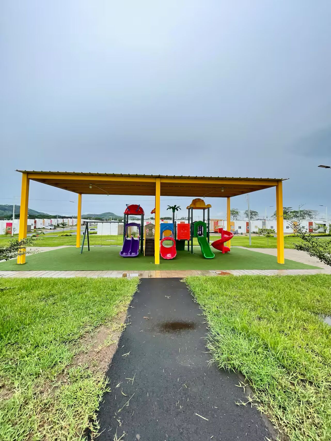 A playground with a yellow canopy and various colorful slides and swings.