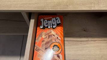A wooden table with a book titled "Flower Market" and a Jenga game box labeled "Jenga Classic" on it.