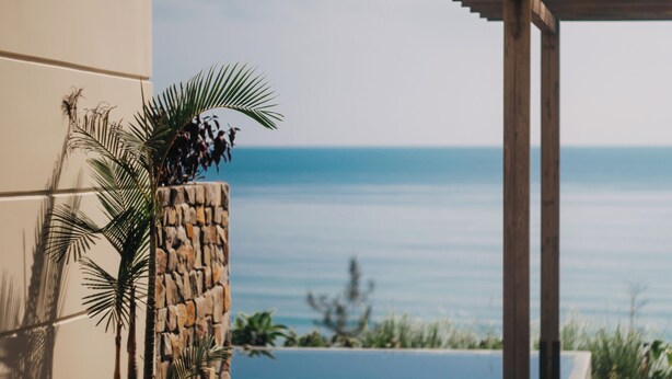 Eine Terrasse mit Meerblick, eine Steinmauer und eine Holzpergola.