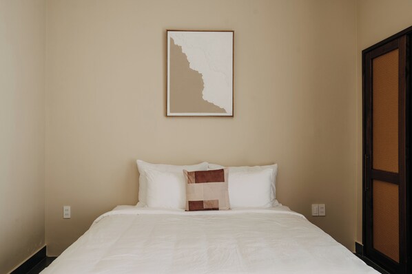 A hotel room with a bed, a wall-mounted artwork, and a door with a woven pattern. - A STAY IN CICI (Hue)