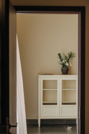 A white cabinet with a vase of flowers on top. - A STAY IN CICI (Hue)