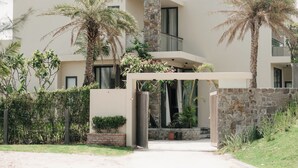 Ein modernes Haus mit Naturstein-Fassade, Palmen und einem Eigengrundstück.
