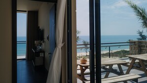Ein Zimmer mit Blick auf den Strand, einem Holztisch und einer Zimmerpflanze.