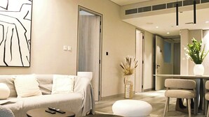 A modern living room with a sofa, a round table, and a dining area with chairs. - Condor Concept 7 - JVC Holiday Homes (Dubai)