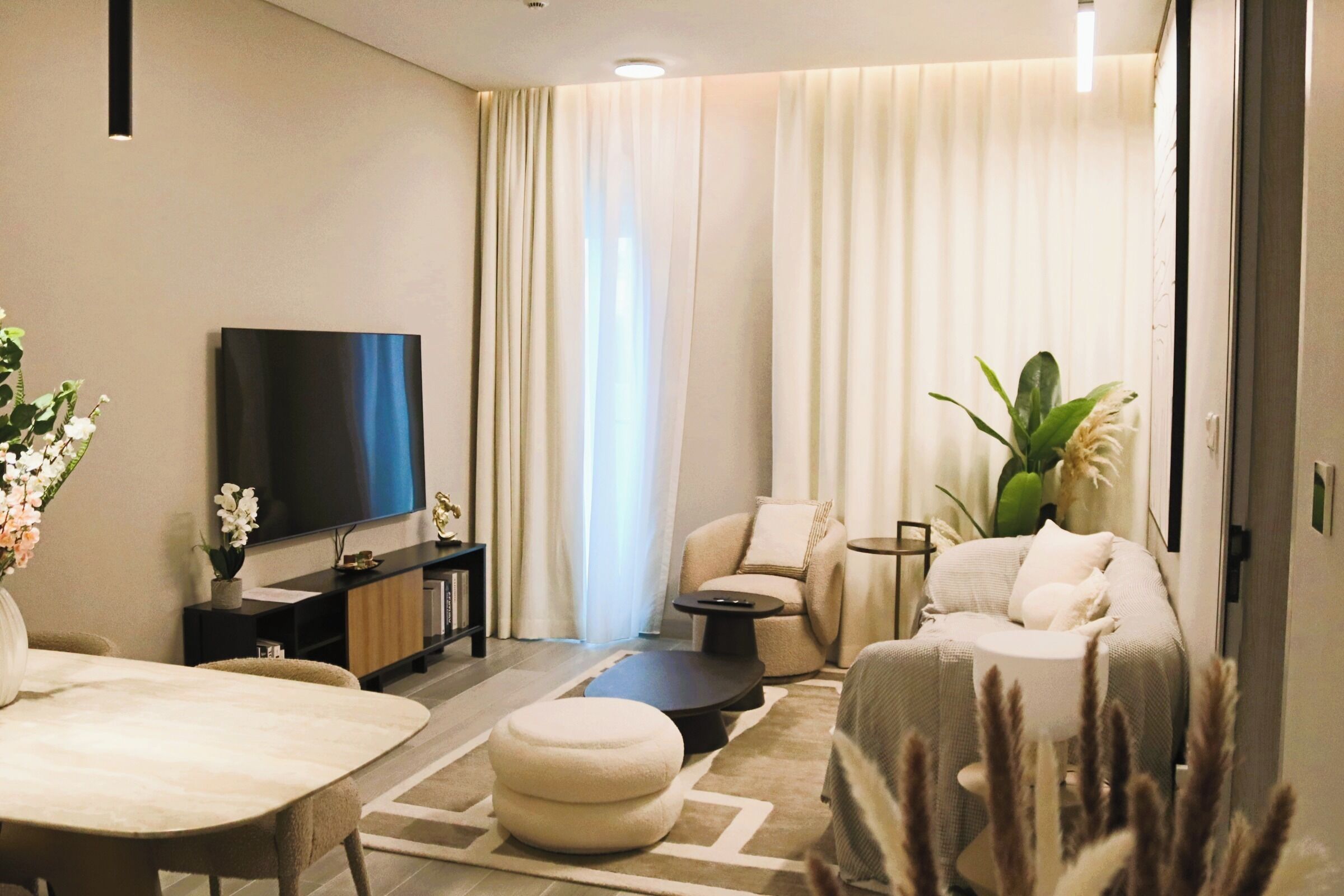 Een moderne woonkamer met een flatscreen televisie, een bank, een salontafel en een eettafel.