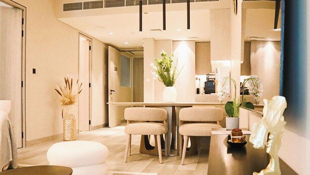 A modern hotel lobby with a reception desk, two plush armchairs, a white sofa, a decorative vase, and a small sculpture. - Condor Concept 7 - JVC Holiday Homes (Dubai)