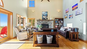 A spacious living room with a stone fireplace, leather furniture, and a bookshelf.