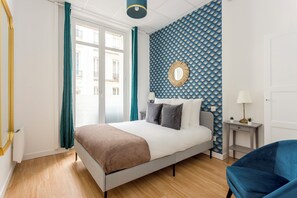 Un dormitorio moderno con una cama, una silla azul y una pared con un estampado azul.