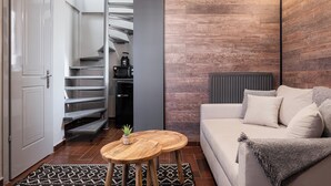 A modern living room with a sofa, a coffee table, and a staircase leading to a kitchen. - Tilemachos by GM Luxury Suites Kalavryta (Καλαβρύτa)