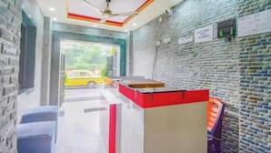 A reception area with a brick wall, a ceiling fan, and a check-in board. - Hotel New Om Shanti International (Kolkata)