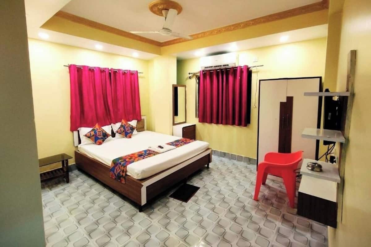 Ein Schlafzimmer mit Bett, Schreibtisch, Stuhl, Spiegel und Deckenventilator.