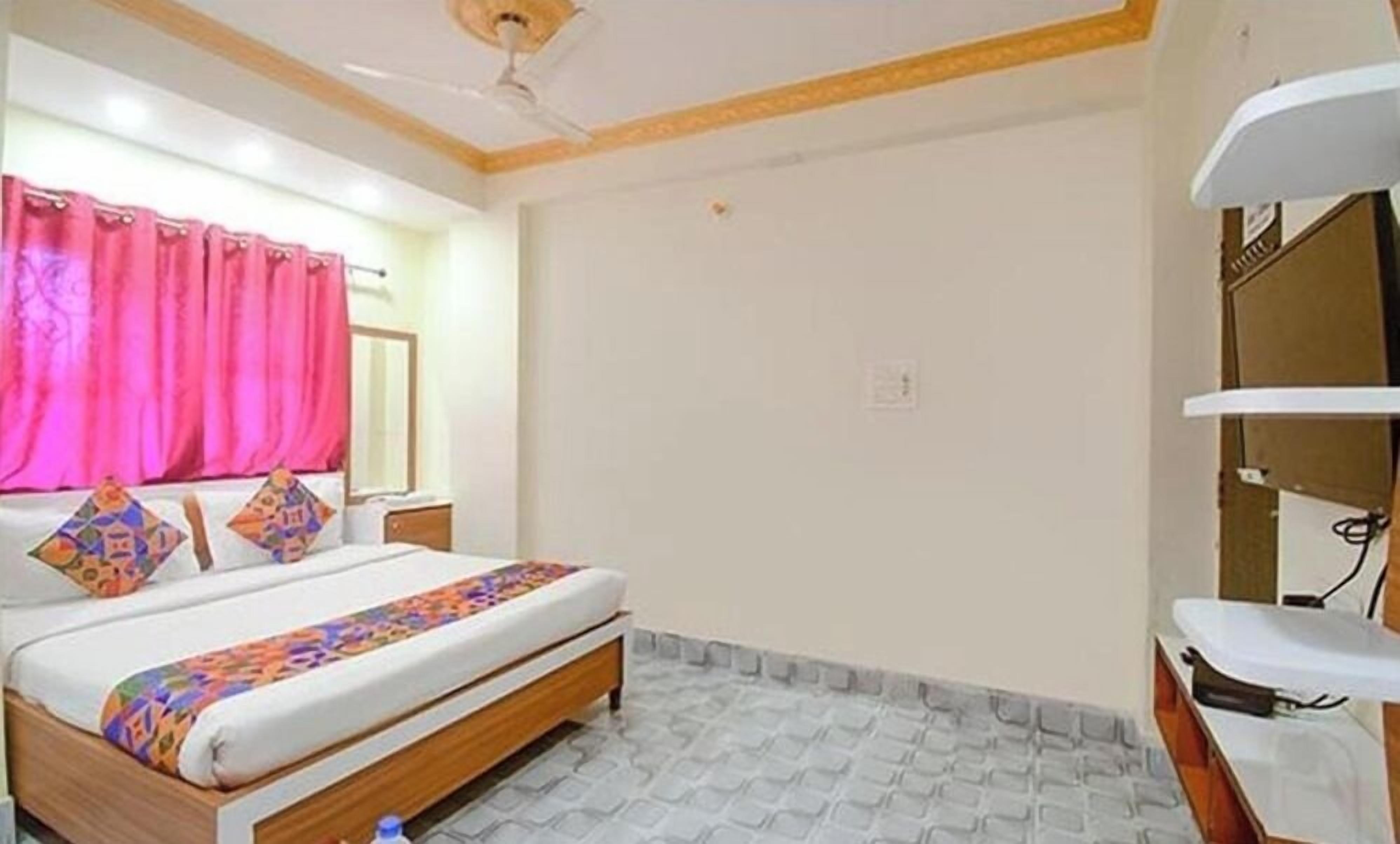 A hotel room with a bed, a nightstand, a mirror, and a bathroom with a sink and toilet.