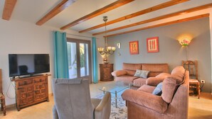 A living room with a TV, sofas, a glass coffee table, and wooden beams on the ceiling. - Studio in Denia with private pool (Denia)