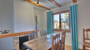 A dining area with a wooden table, chairs, a vase, and a window with curtains. - Studio in Denia with private pool (Denia)