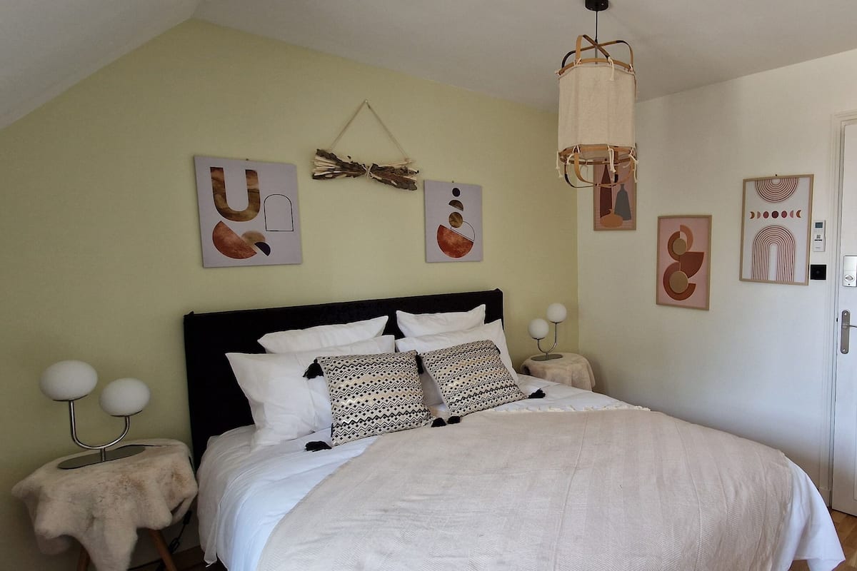 Un dormitorio con cama, mesitas de noche y decoración en la pared.