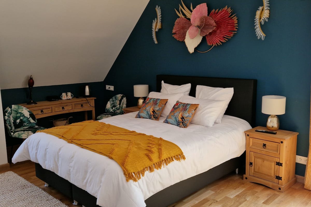 Un dormitorio con cama, mesitas de noche, cómoda y ventana con cortinas.