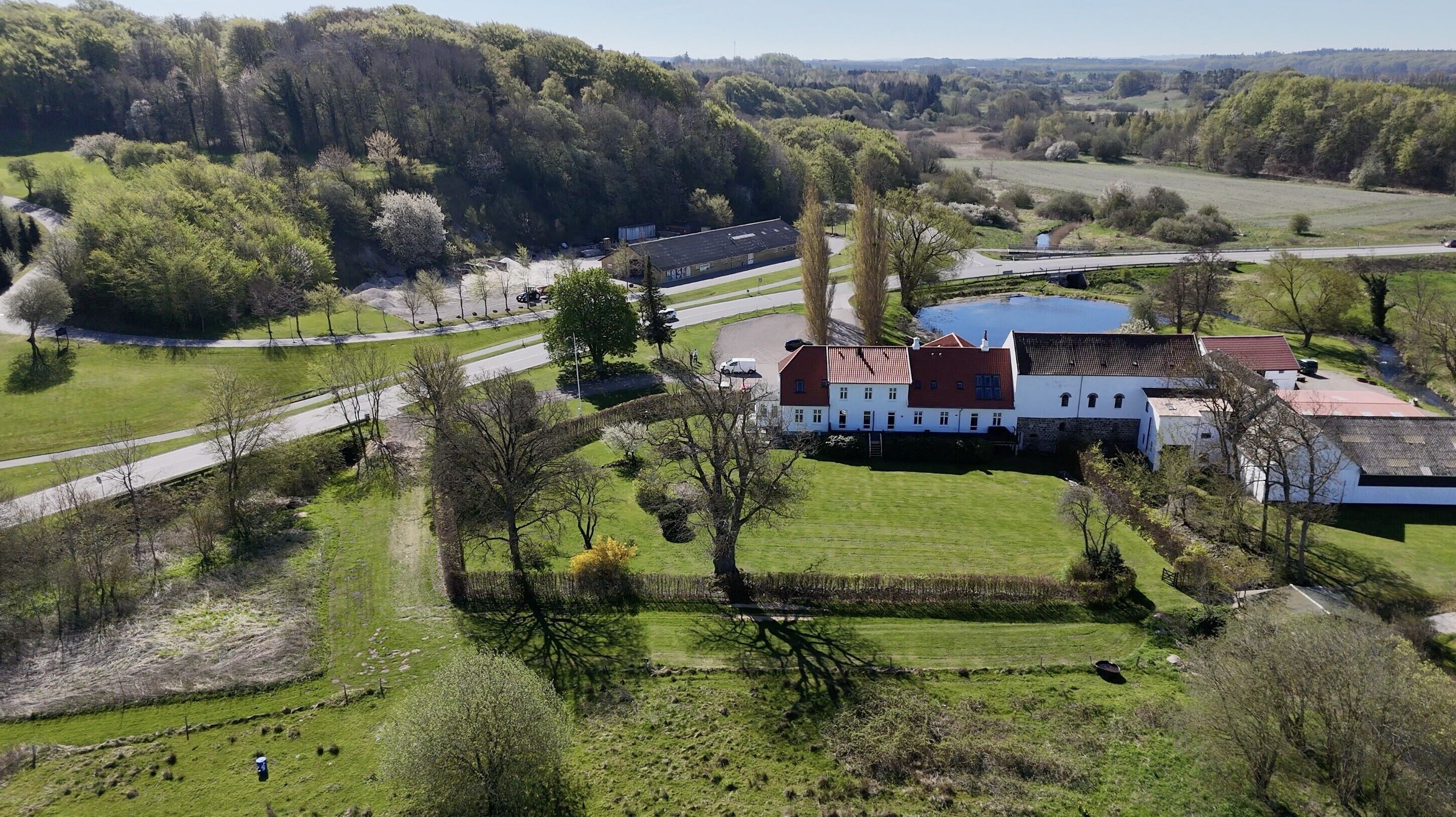 A large estate with a main building, expansive green fields, and a road.