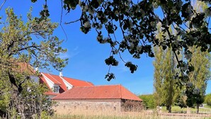 A stone building with a red roof, a pond, and surrounding greenery. - Aamølle Gæstgiveri (Hadsund)